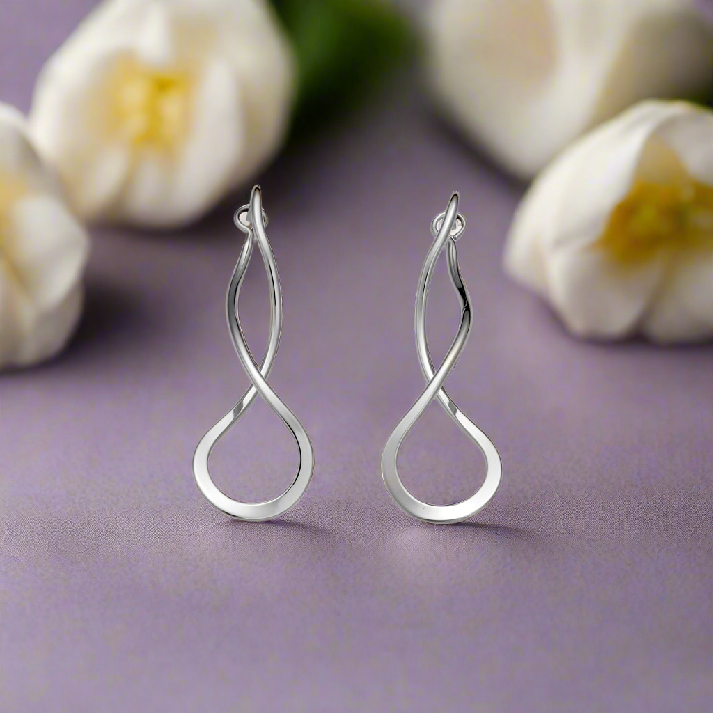 Photo of Endless Braid Earrings in a decorative scene, designed by -, available at Plumb Gold & Plumb Silver