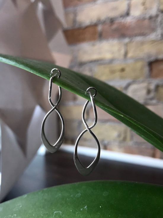 Photo of "Feather" Earrings in a decorative scene, designed by , available at Plumb Gold & Plumb Silver