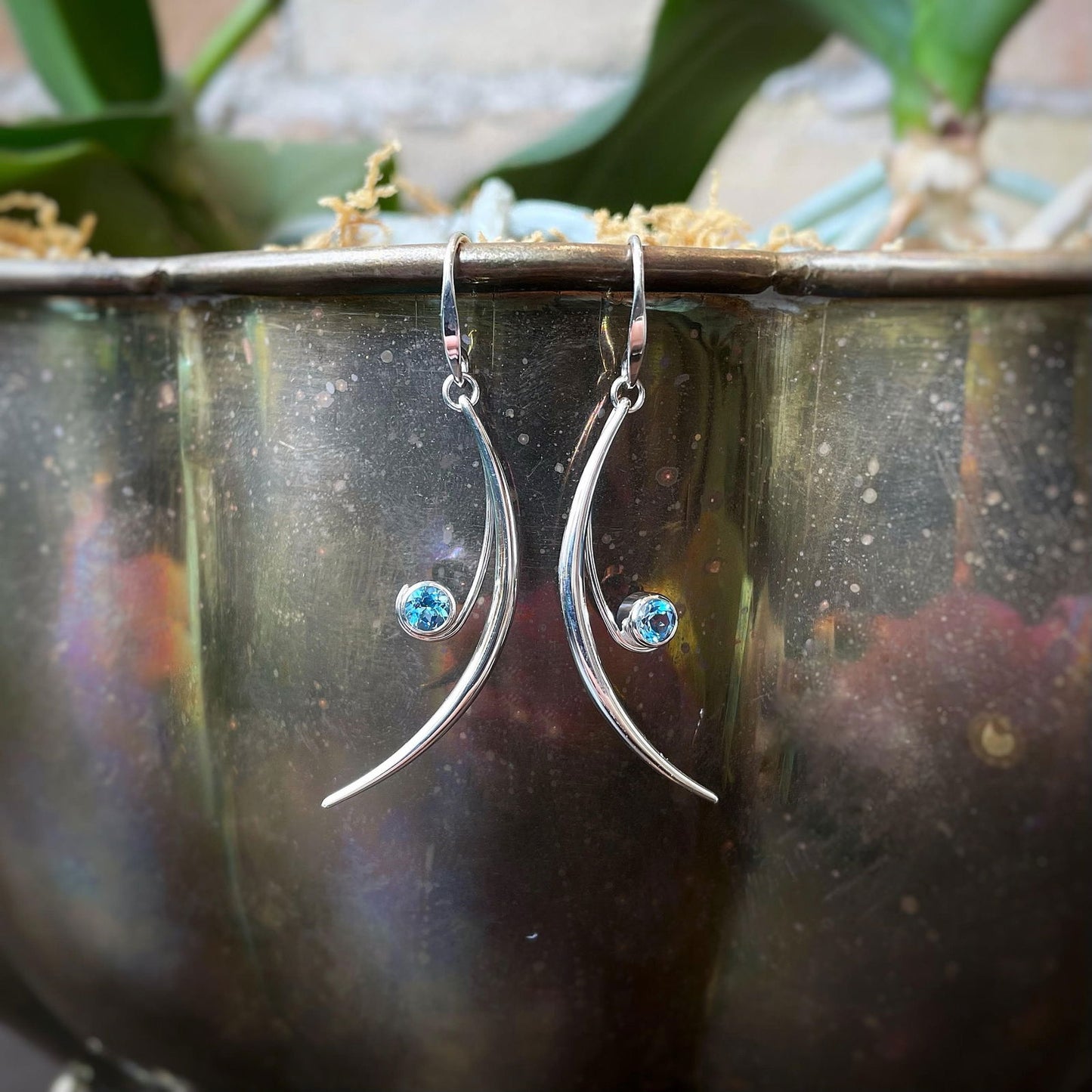 Photo of "Featherstone" Blue Topaz Earrings in a decorative scene, designed by , available at Plumb Gold & Plumb Silver
