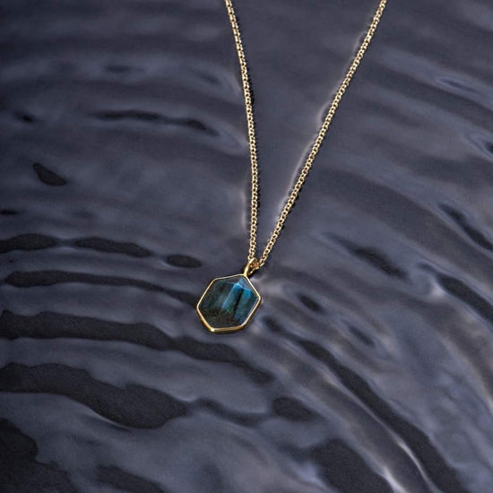 Photo of “Geo” Labradorite Pendant in a decorative scene, designed by , available at Plumb Gold & Plumb Silver