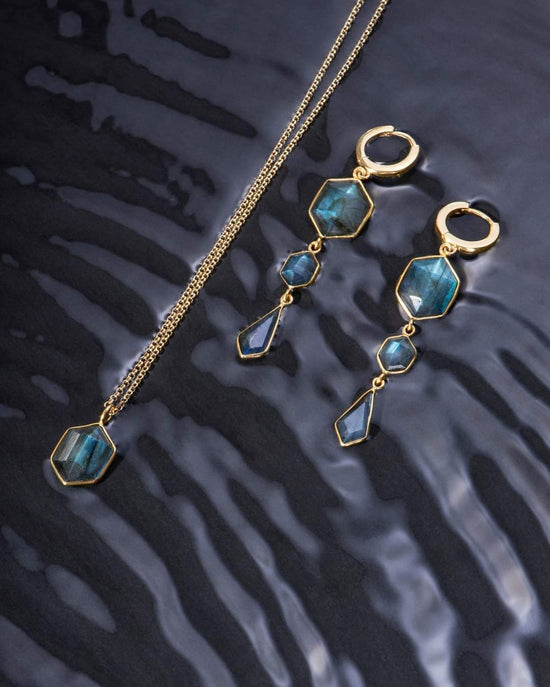 Photo of “Geo” Labradorite Pendant in a decorative scene, designed by , available at Plumb Gold & Plumb Silver