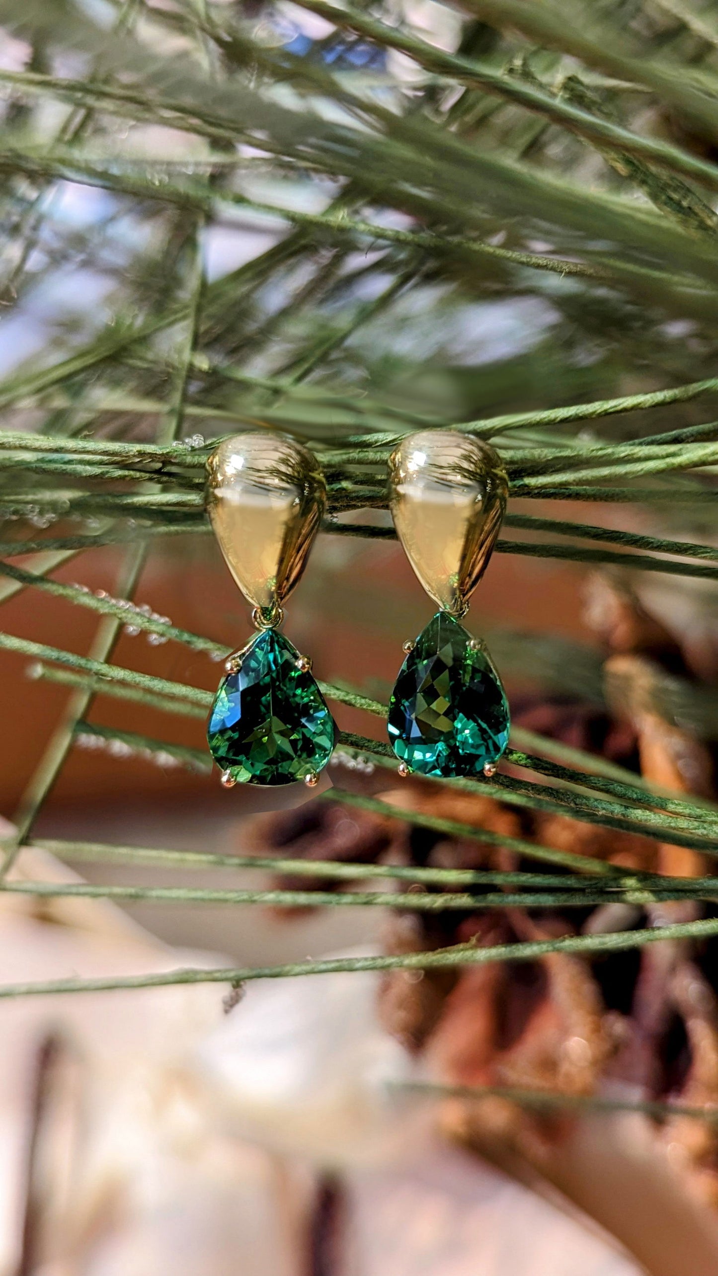 Photo of Green Tourmaline Drop Earrings in a decorative scene, designed by , available at Plumb Gold & Plumb Silver
