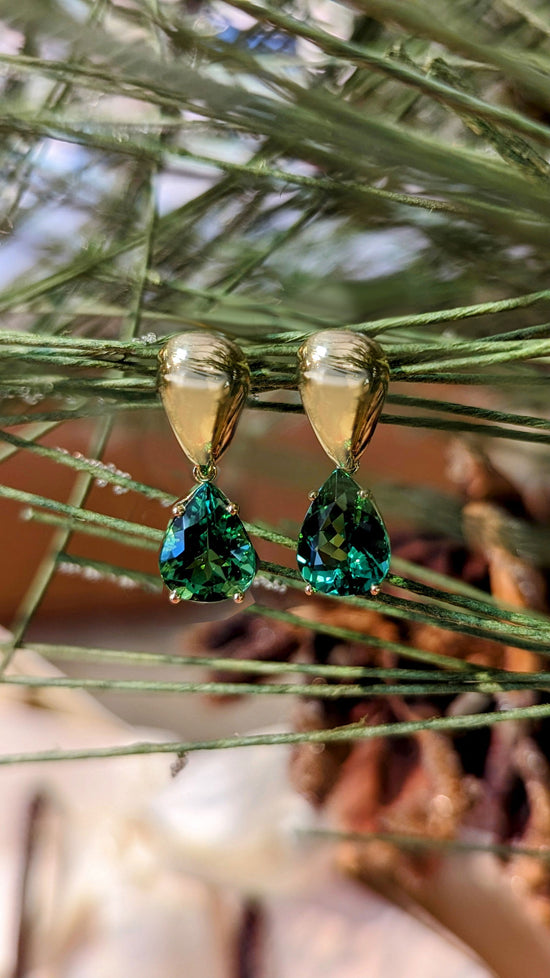 Photo of Green Tourmaline Drop Earrings in a decorative scene, designed by , available at Plumb Gold & Plumb Silver