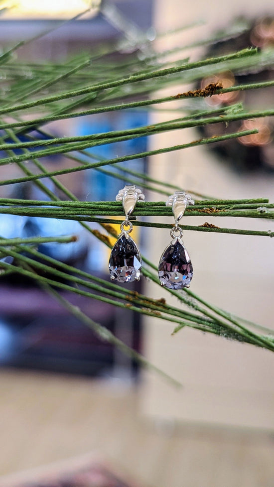 Photo of Grey Spinel Dangle Earrings in a decorative scene, designed by , available at Plumb Gold & Plumb Silver