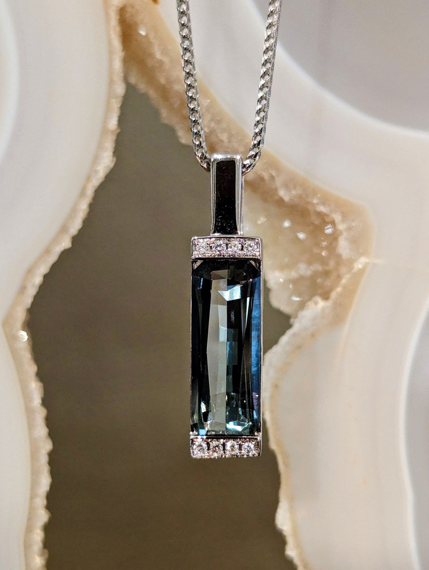 Photo of Grey Tourmaline Bar Pendant in a decorative scene, designed by , available at Plumb Gold & Plumb Silver