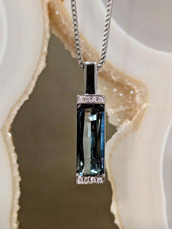 Photo of Grey Tourmaline Bar Pendant in a decorative scene, designed by , available at Plumb Gold & Plumb Silver