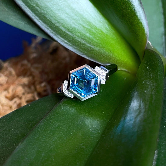 Photo of Hexagonal Blue Topaz Ring in a decorative scene, designed by , available at Plumb Gold & Plumb Silver