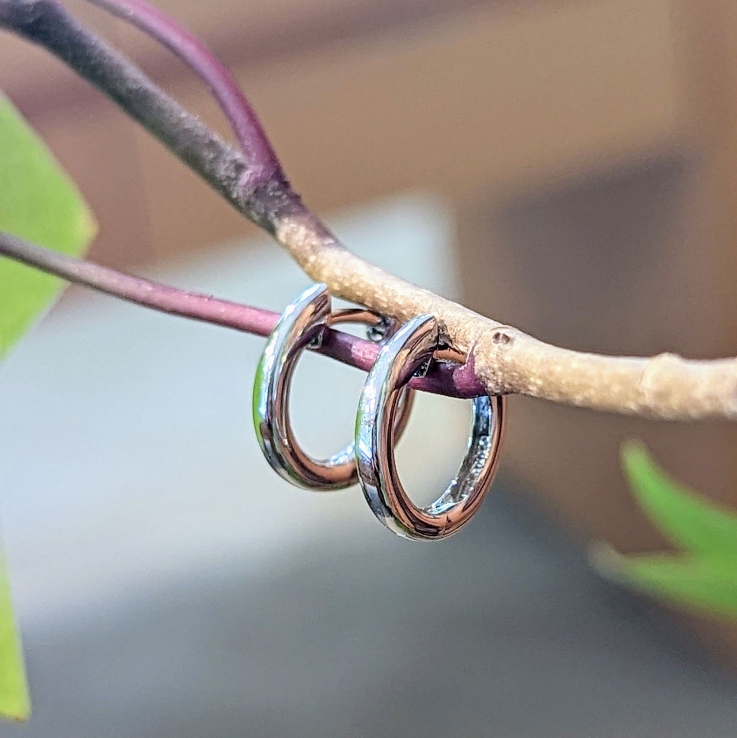 Photo of Hinged Huggie Hoops in a decorative scene, designed by , available at Plumb Gold & Plumb Silver
