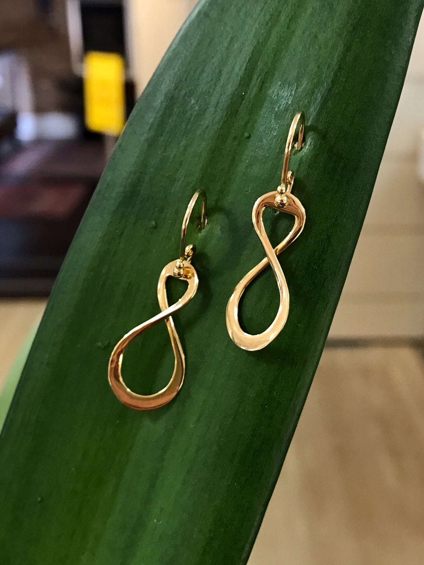 Photo of Infinity Dangles in a decorative scene, designed by , available at Plumb Gold & Plumb Silver