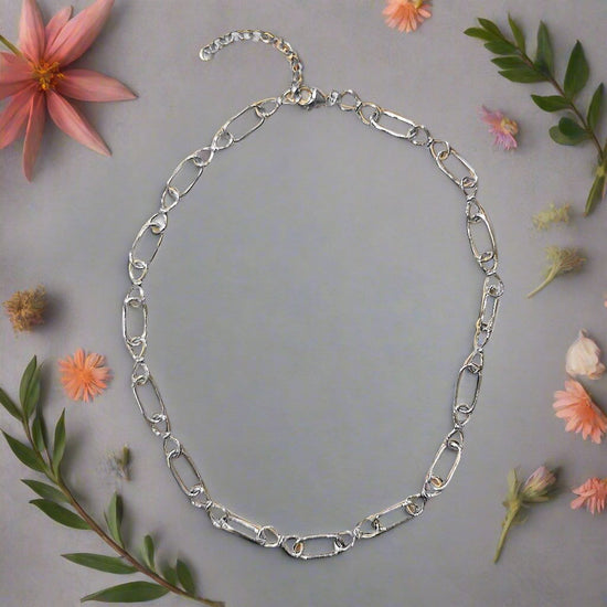 Photo of Infinity Link Chain in a decorative scene, designed by , available at Plumb Gold & Plumb Silver