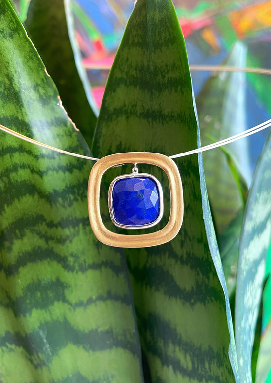 Photo of "Keops" Lapis Pendant in a decorative scene, designed by , available at Plumb Gold & Plumb Silver