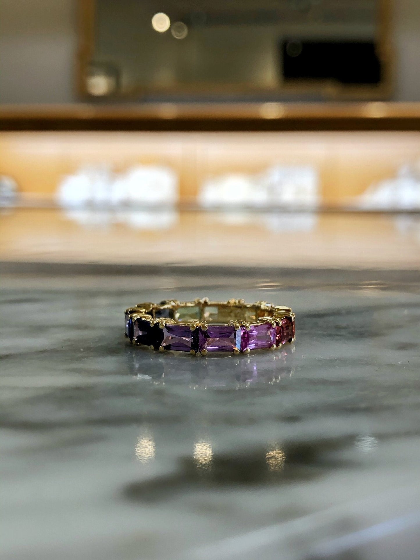 Photo of Kim Collins Rainbow Sapphire Band in a decorative scene, designed by , available at Plumb Gold & Plumb Silver