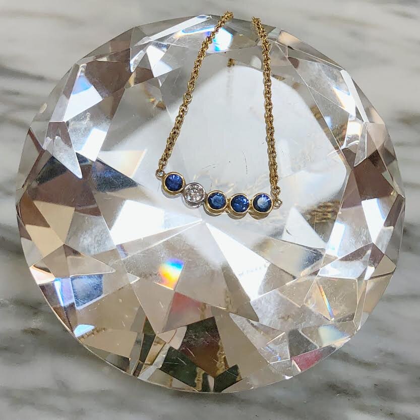 Photo of Kim Collins Sapphire &amp; Diamond "Dots" Necklace in a decorative scene, designed by , available at Plumb Gold & Plumb Silver