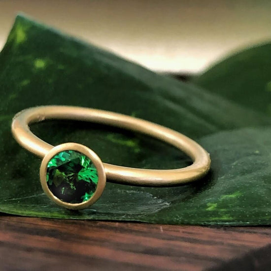 Photo of Kim Collins Tsavorite Yum Drop in a decorative scene, designed by , available at Plumb Gold & Plumb Silver