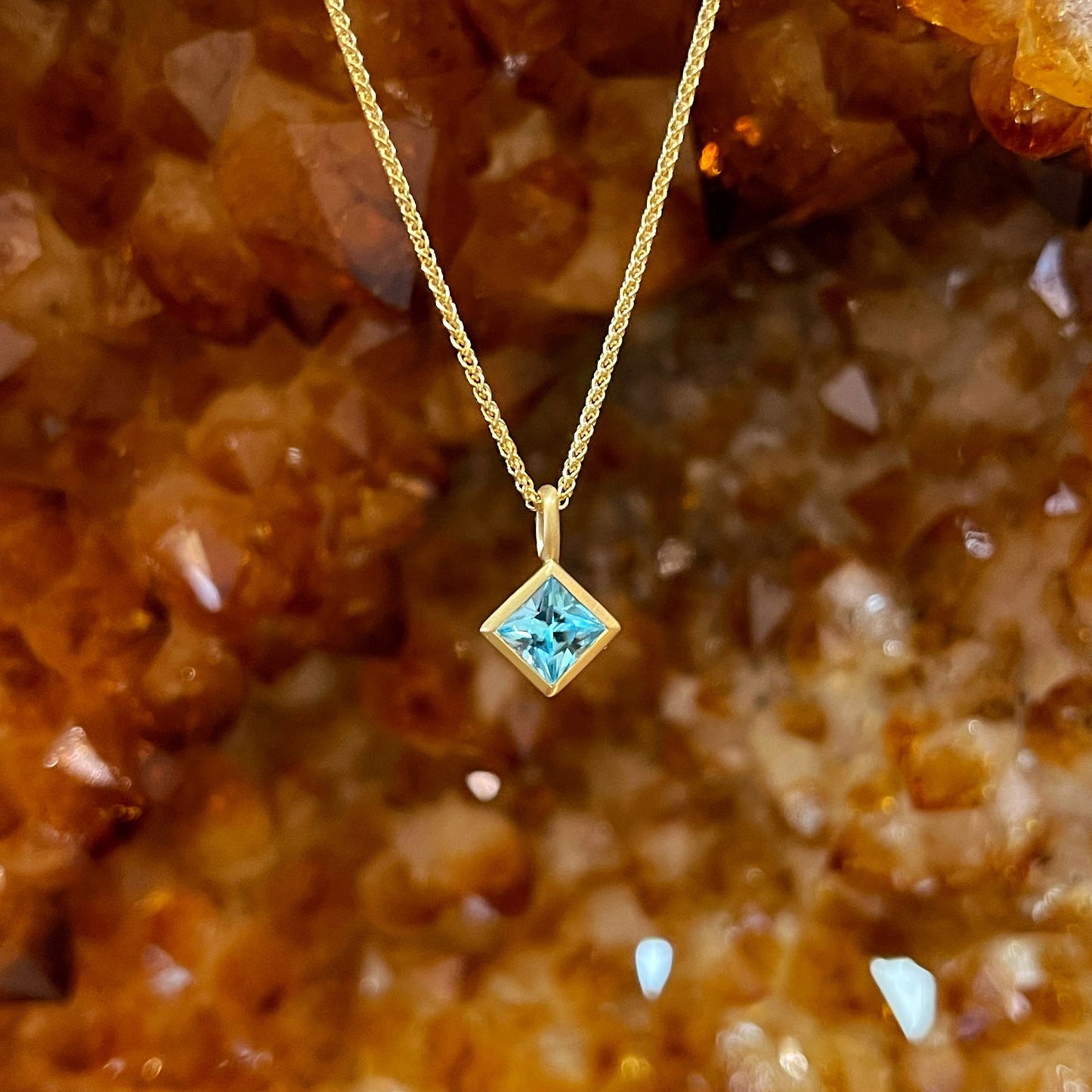 Photo of Kimberly Collins Blue Zircon Pendant in a decorative scene, designed by , available at Plumb Gold & Plumb Silver