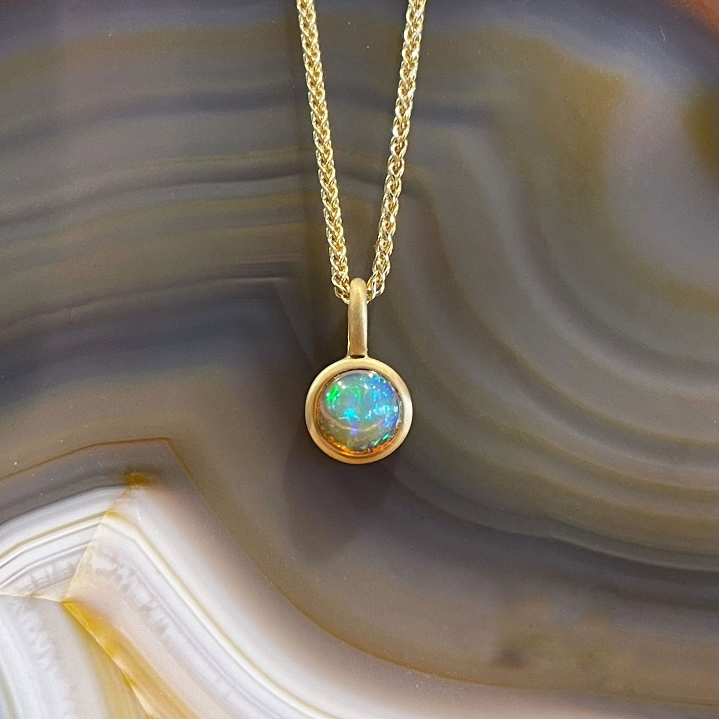 Photo of Kimberly Collins Ethiopian Opal Pendant in a decorative scene, designed by , available at Plumb Gold & Plumb Silver