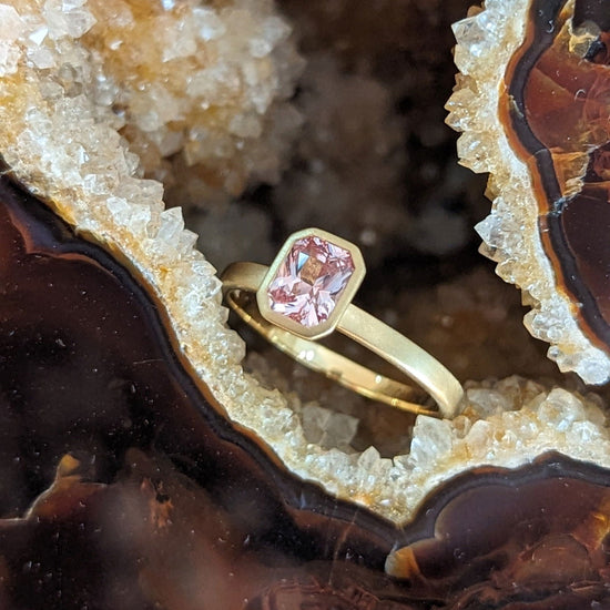 Photo of Kimberly Collins Peach Sapphire Yum Drop Ring in a decorative scene, designed by , available at Plumb Gold & Plumb Silver