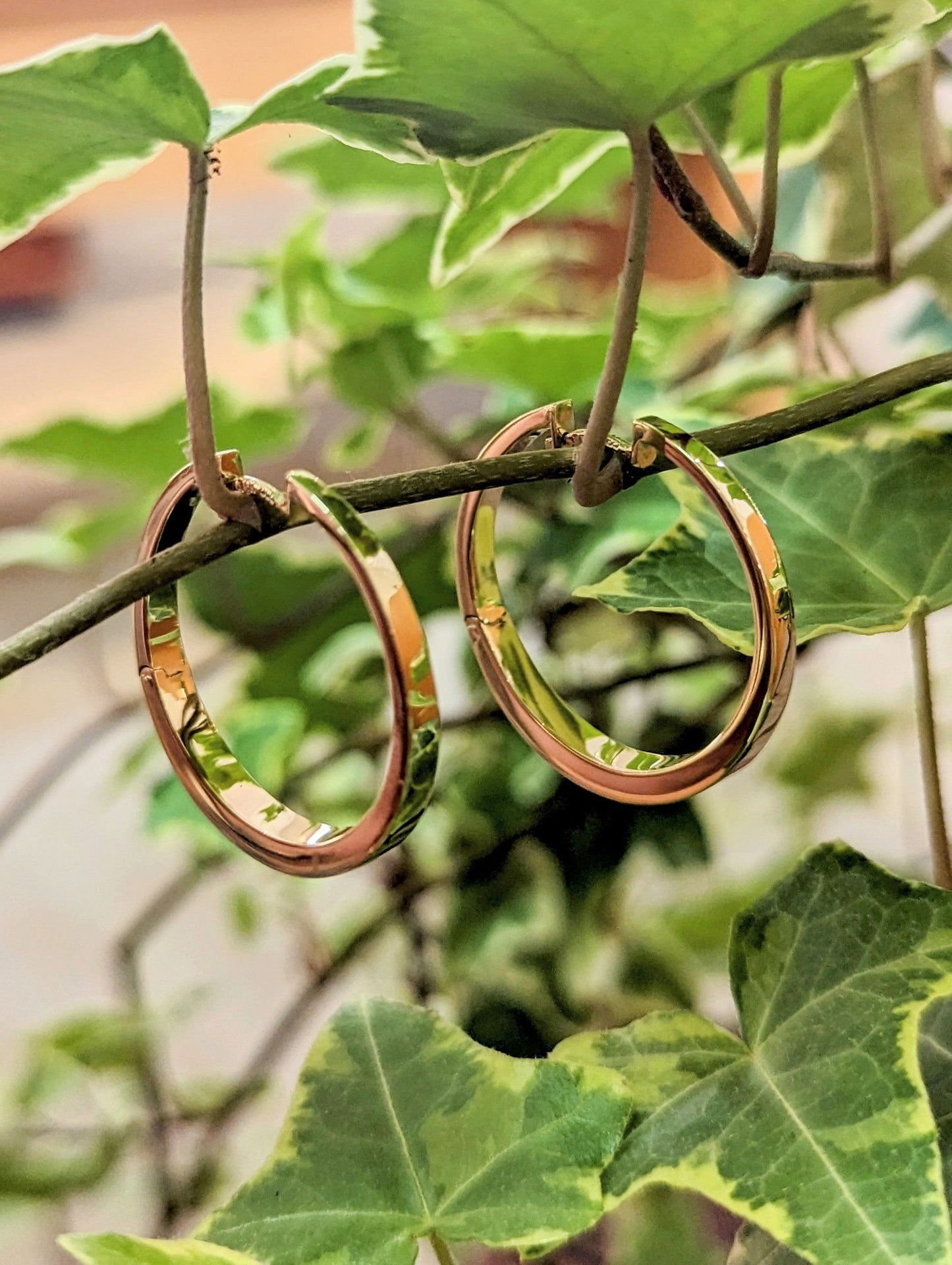 Photo of Large Tapered Gold Hoops in a decorative scene, designed by , available at Plumb Gold & Plumb Silver