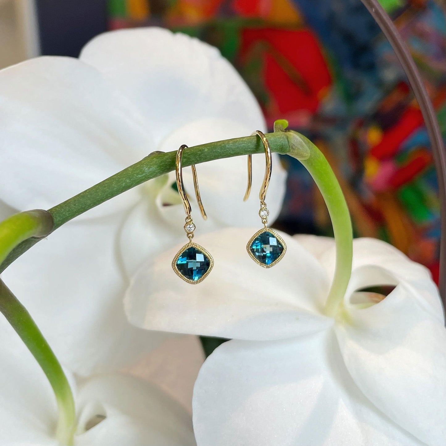 Photo of London Blue Topaz Dangle Earrings in a decorative scene, designed by , available at Plumb Gold & Plumb Silver