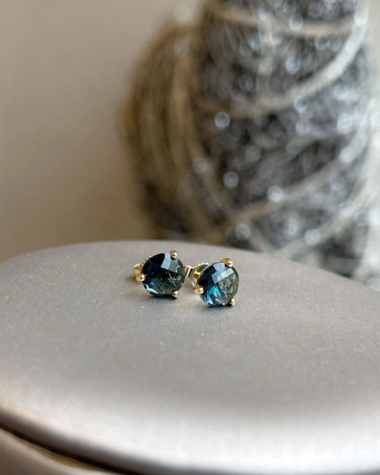 Photo of London Blue Topaz Studs in a decorative scene, designed by , available at Plumb Gold & Plumb Silver