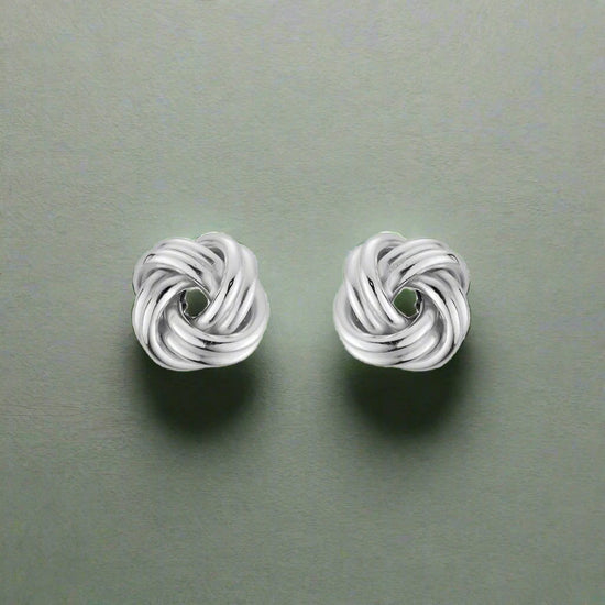 Photo of Love Knot Earrings in a decorative scene, designed by , available at Plumb Gold & Plumb Silver