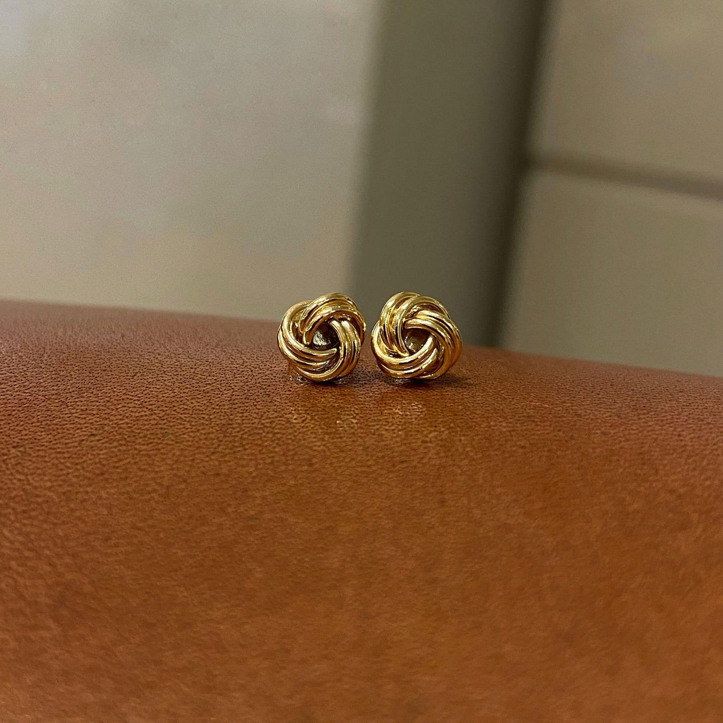 Photo of Love Knot Stud Earrings in a decorative scene, designed by , available at Plumb Gold & Plumb Silver