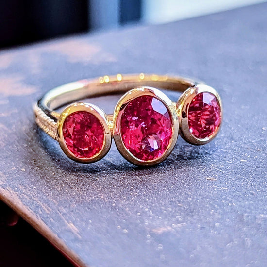 Photo of Mahenge Spinel Stackable 3-Stone Ring in a decorative scene, designed by , available at Plumb Gold & Plumb Silver