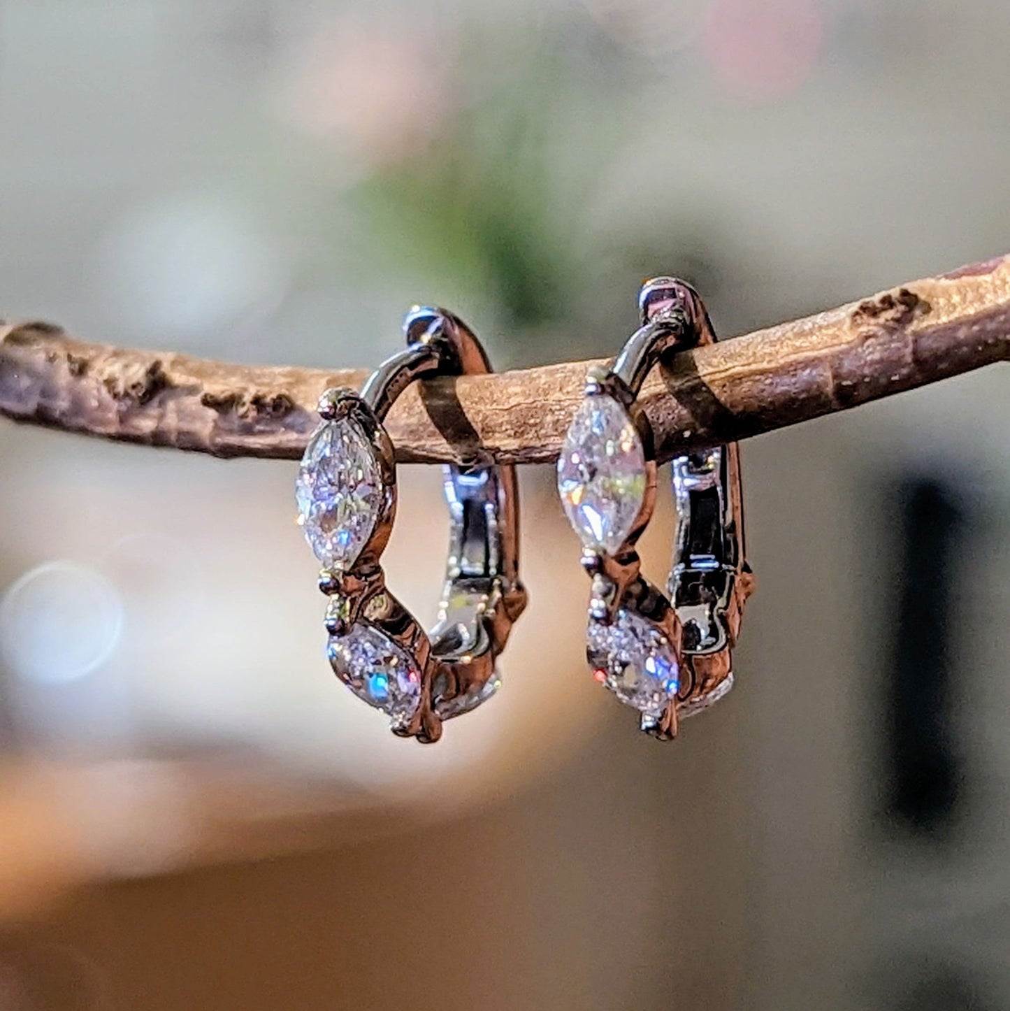 Photo of Marquise CZ Huggie Earrings in a decorative scene, designed by , available at Plumb Gold & Plumb Silver