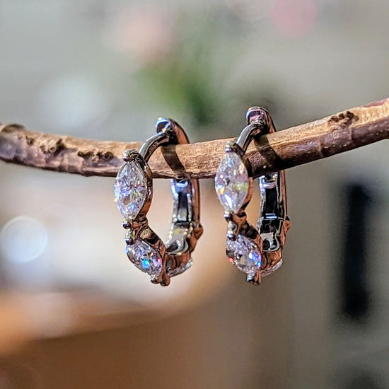 Photo of Marquise CZ Huggie Earrings in a decorative scene, designed by , available at Plumb Gold & Plumb Silver