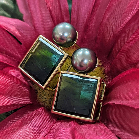 Photo of Mirror Cut Tourmaline and Tahitian Pearl Earrings in a decorative scene, designed by , available at Plumb Gold & Plumb Silver