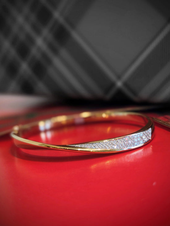 Photo of Mobius Bangle in a decorative scene, designed by , available at Plumb Gold & Plumb Silver