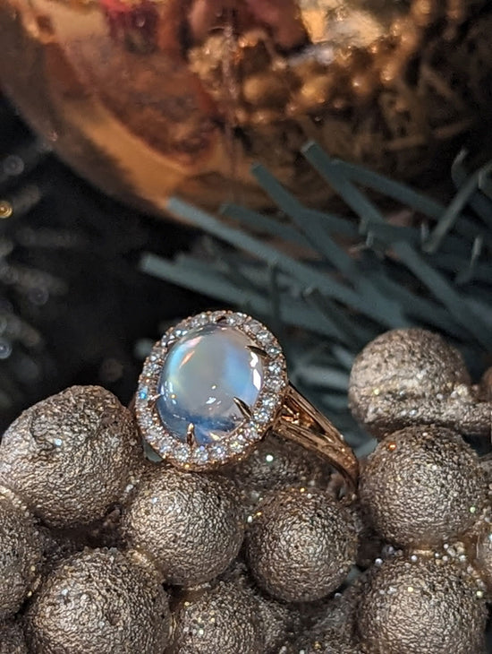 Photo of Moonstone halo Ring in a decorative scene, designed by , available at Plumb Gold & Plumb Silver