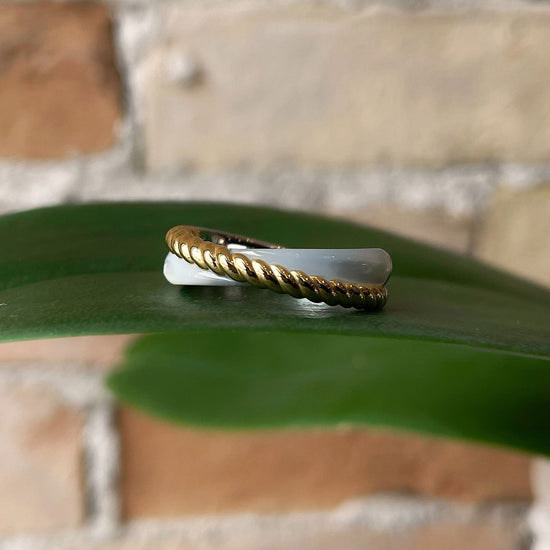 Photo of Mother of Pearl Crossover Ring in a decorative scene, designed by , available at Plumb Gold & Plumb Silver