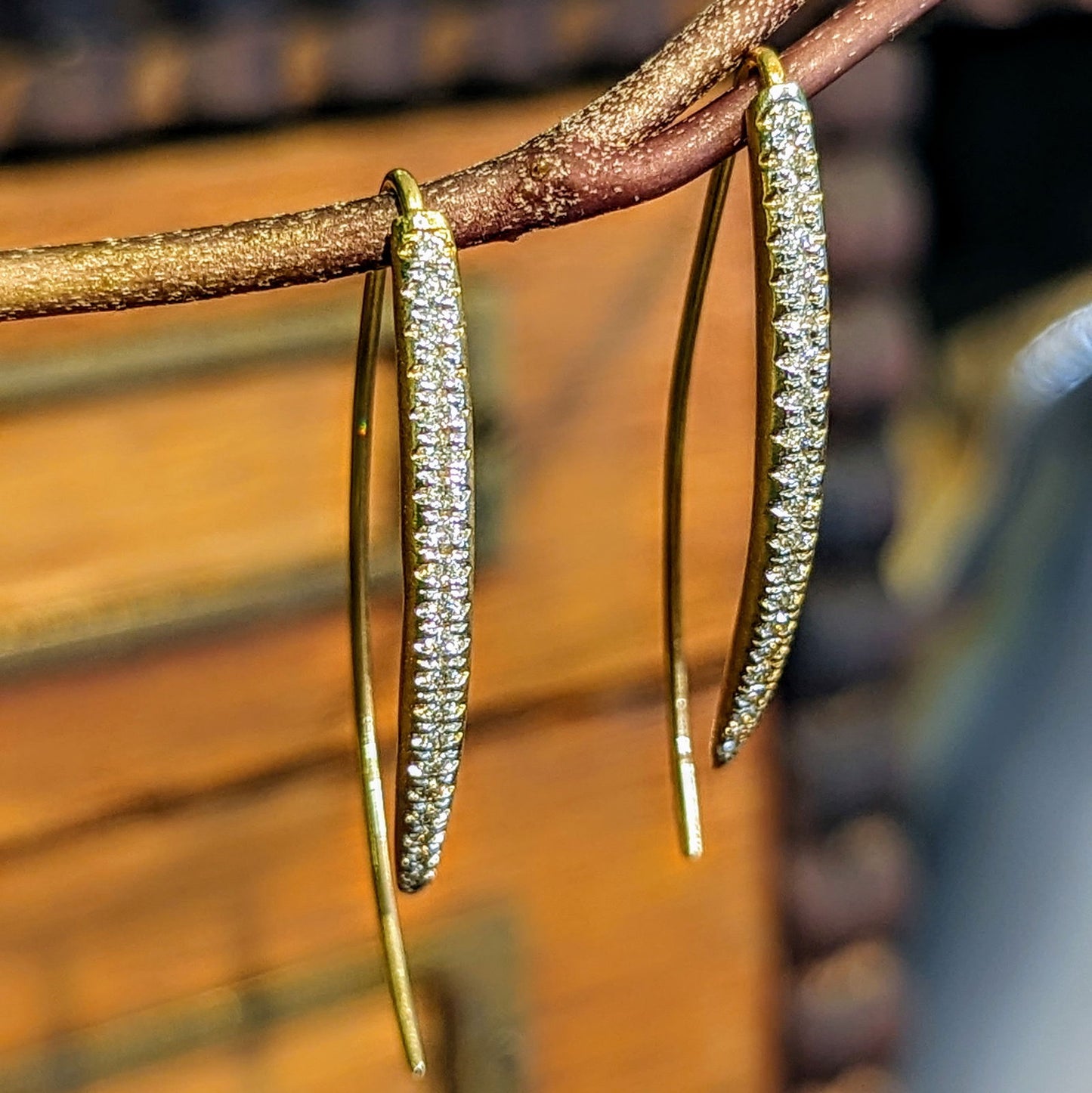 Photo of Pavé bowed hook earring in a decorative scene, designed by , available at Plumb Gold & Plumb Silver
