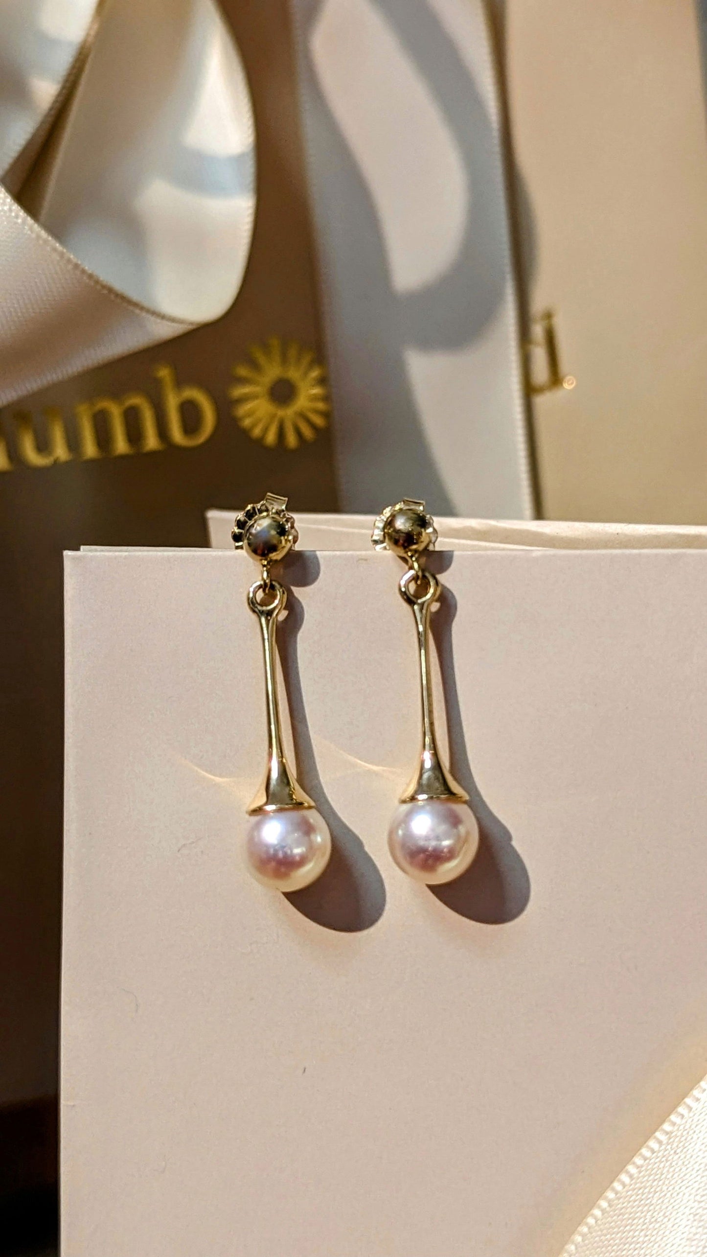 Photo of Pearl Drop Earrings in a decorative scene, designed by , available at Plumb Gold & Plumb Silver