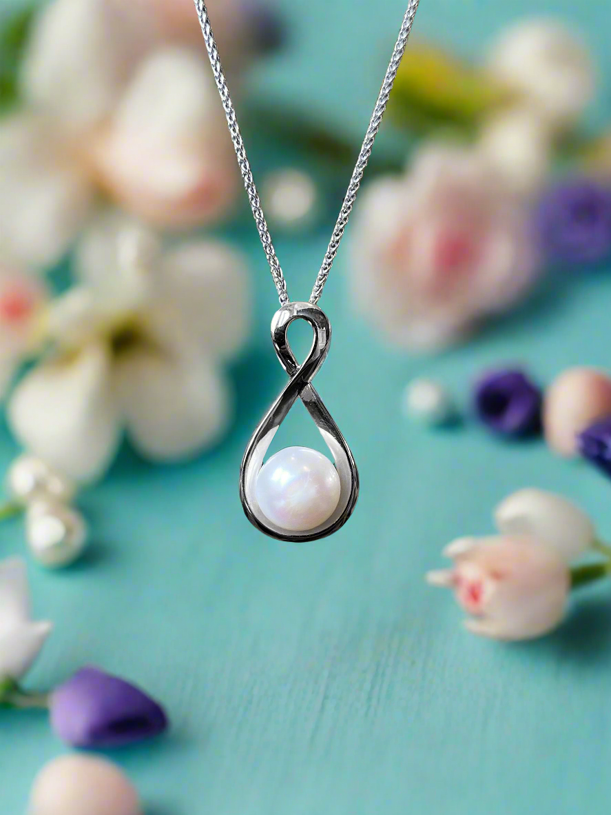 Photo of Pearl Infinity Necklace in a decorative scene, designed by , available at Plumb Gold & Plumb Silver