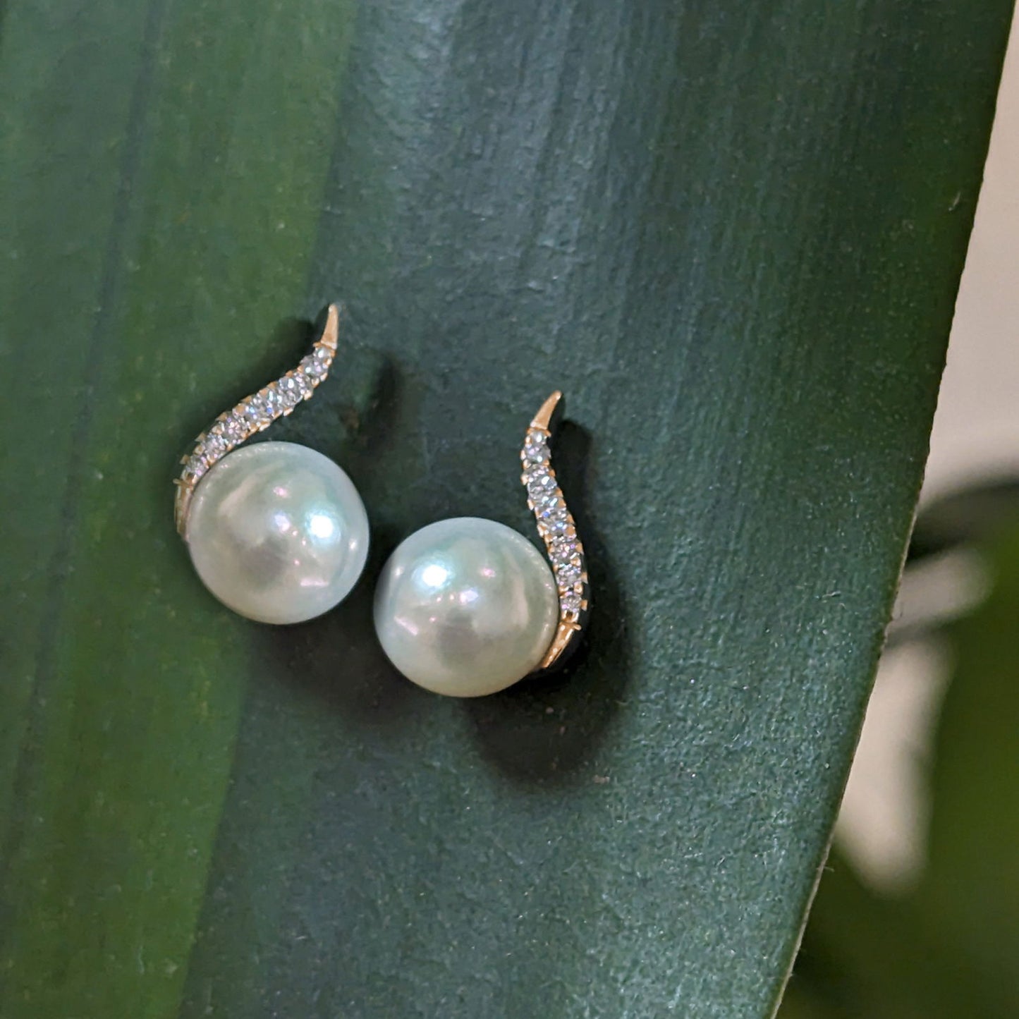 Photo of Pearl and Diamond Curve Stud in a decorative scene, designed by , available at Plumb Gold & Plumb Silver