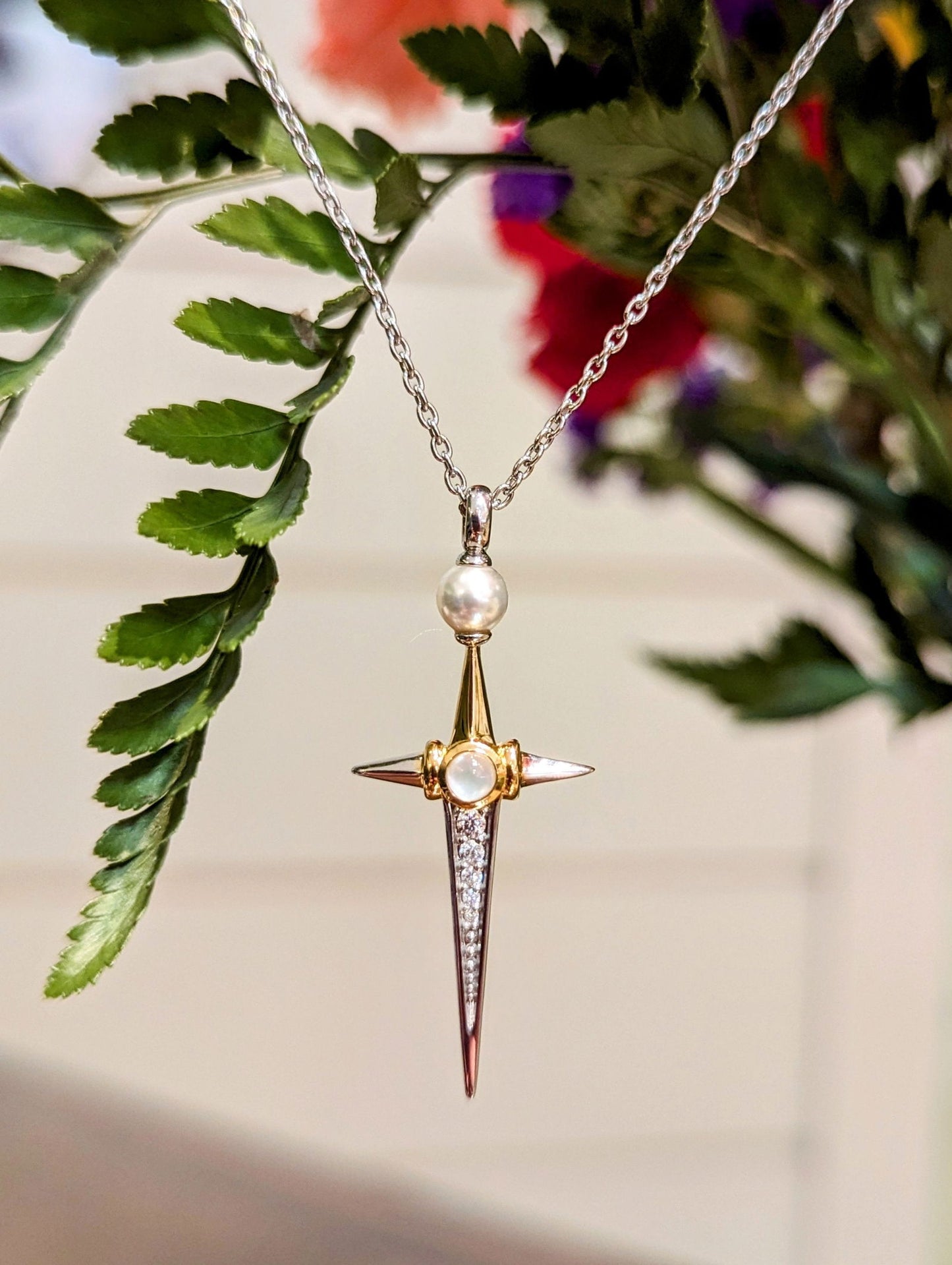 Photo of Pearl and cubic zirconia cross in a decorative scene, designed by , available at Plumb Gold & Plumb Silver