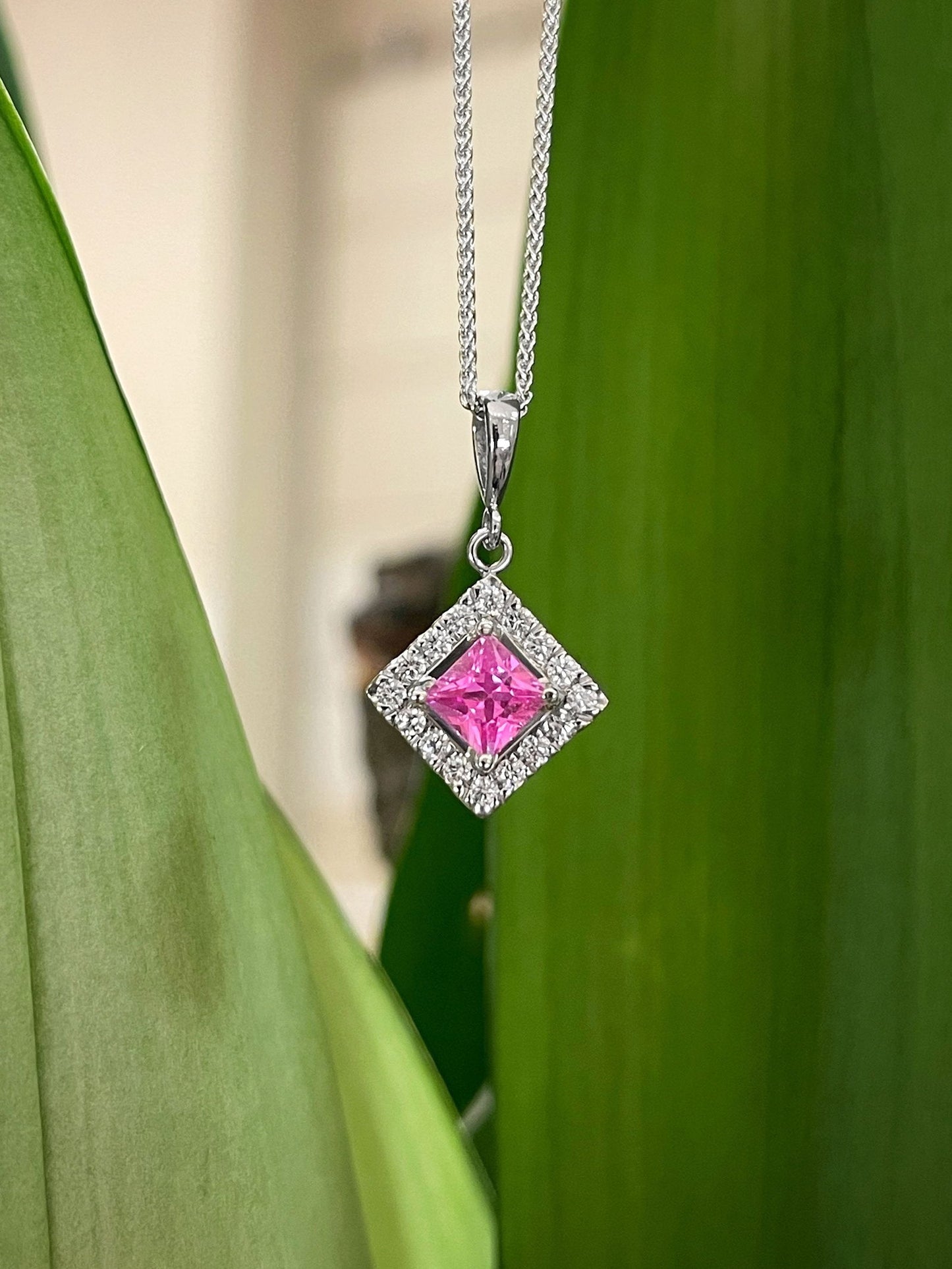 Photo of Pink Sapphire & Diamond Pendant in a decorative scene, designed by , available at Plumb Gold & Plumb Silver