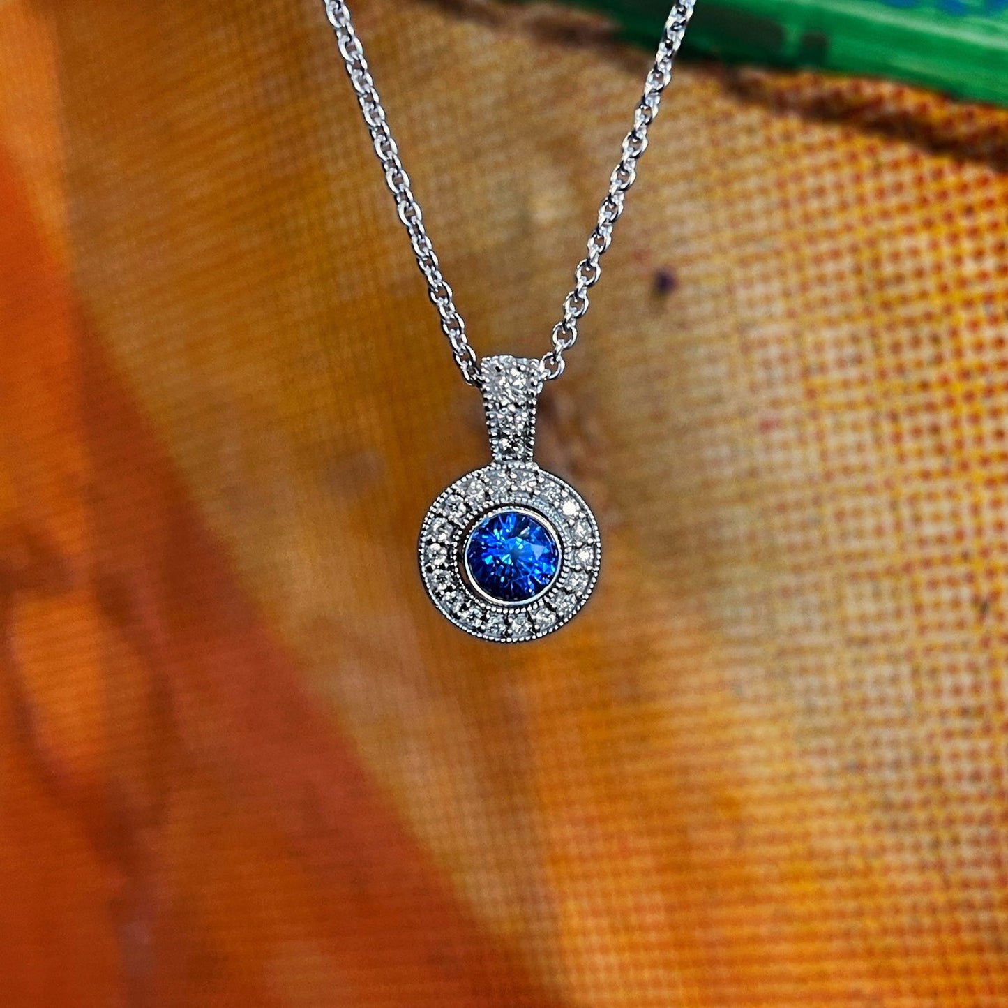 Photo of Plumb Gold Original Blue Sapphire and Diamond Pendant in a decorative scene, designed by , available at Plumb Gold & Plumb Silver