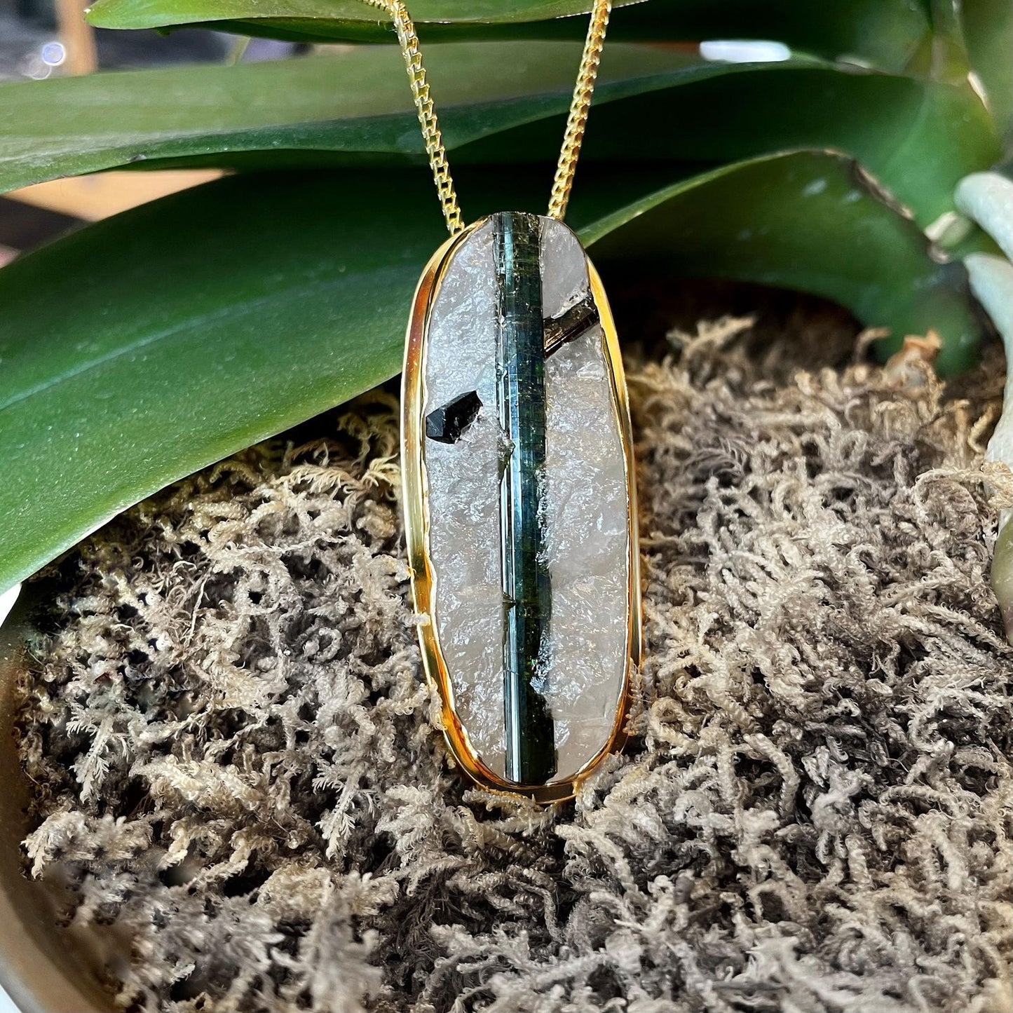 Photo of Plumb Gold Original Tourmalinated Quartz Pendant in a decorative scene, designed by , available at Plumb Gold & Plumb Silver
