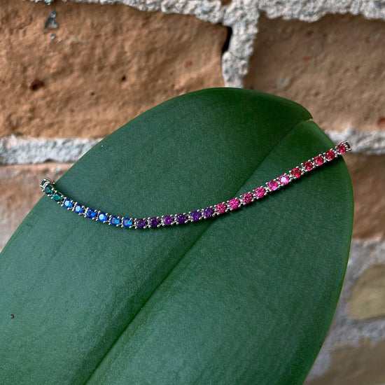 Photo of Rainbow Tennis Bracelet in a decorative scene, designed by , available at Plumb Gold & Plumb Silver