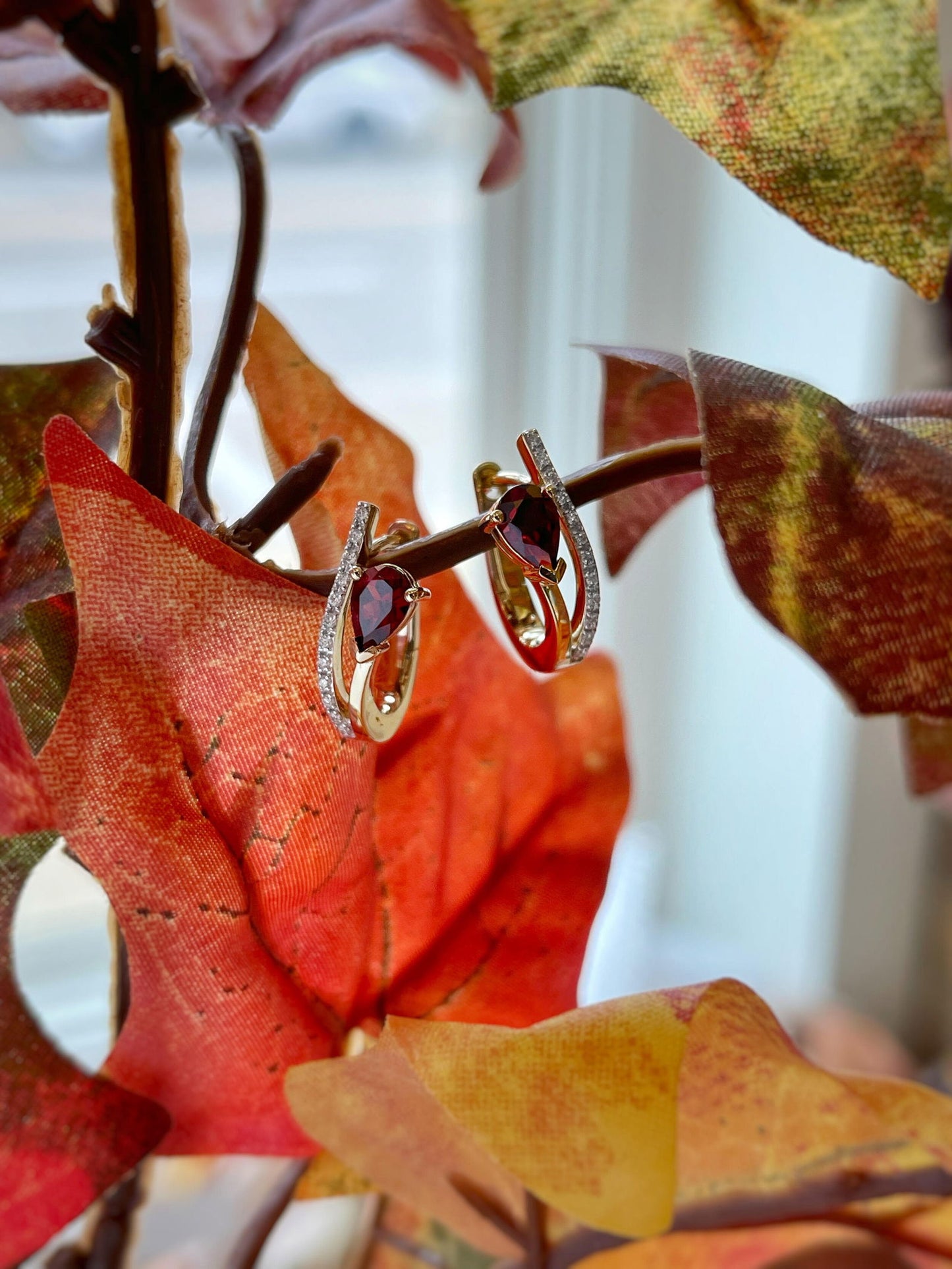 Photo of Red Garnet Swoop Hoops in a decorative scene, designed by , available at Plumb Gold & Plumb Silver