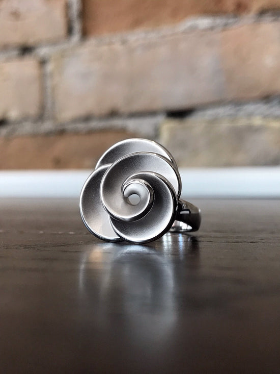 Photo of Rosette Ring in a decorative scene, designed by , available at Plumb Gold & Plumb Silver
