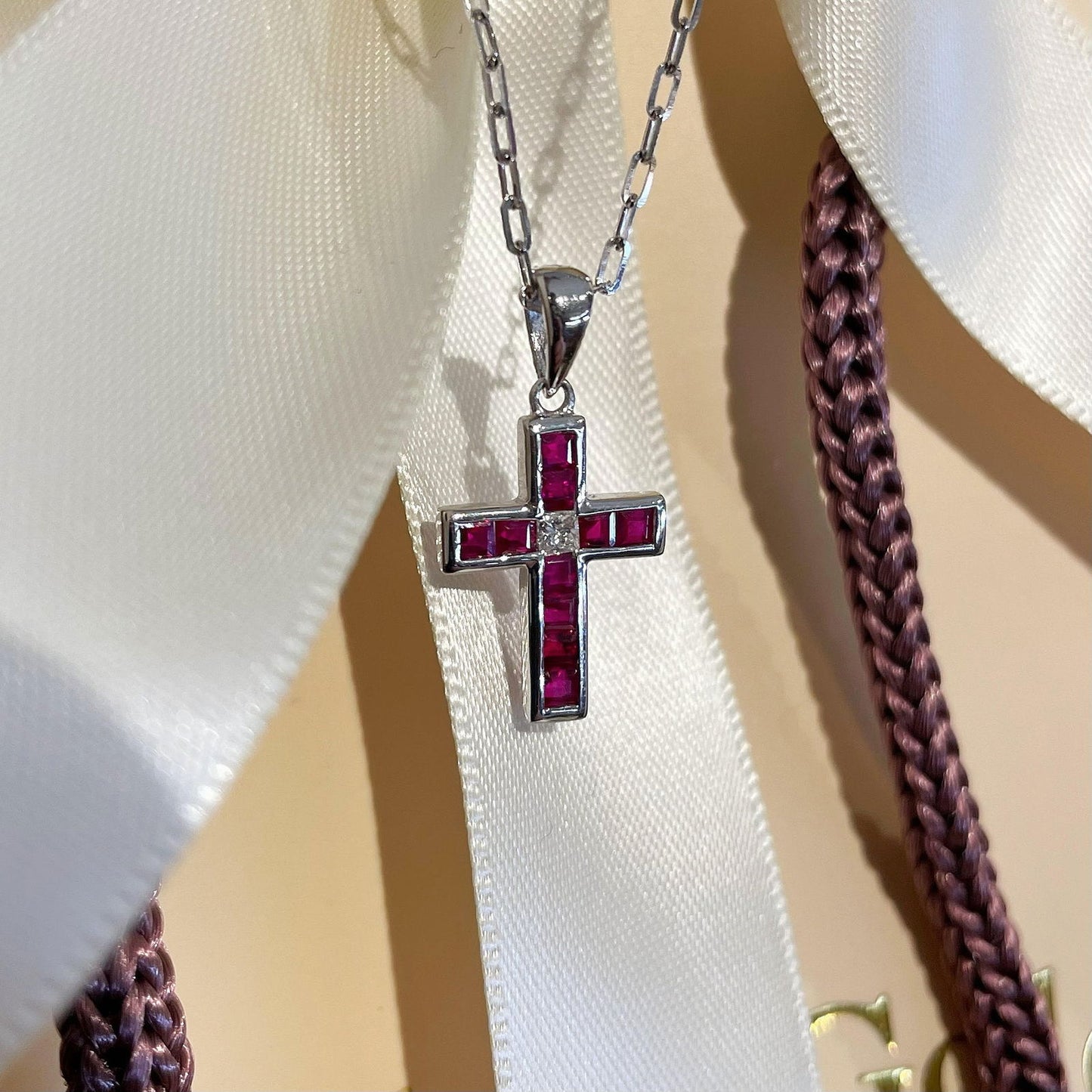Photo of Ruby Diamond Cross Pendant in a decorative scene, designed by , available at Plumb Gold & Plumb Silver