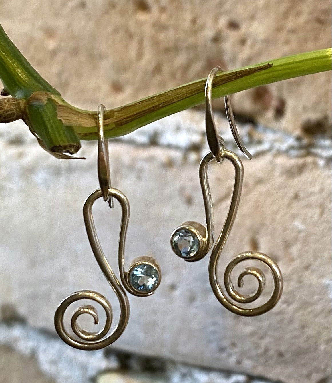 Photo of "Script" Blue Topaz Earrings in a decorative scene, designed by , available at Plumb Gold & Plumb Silver