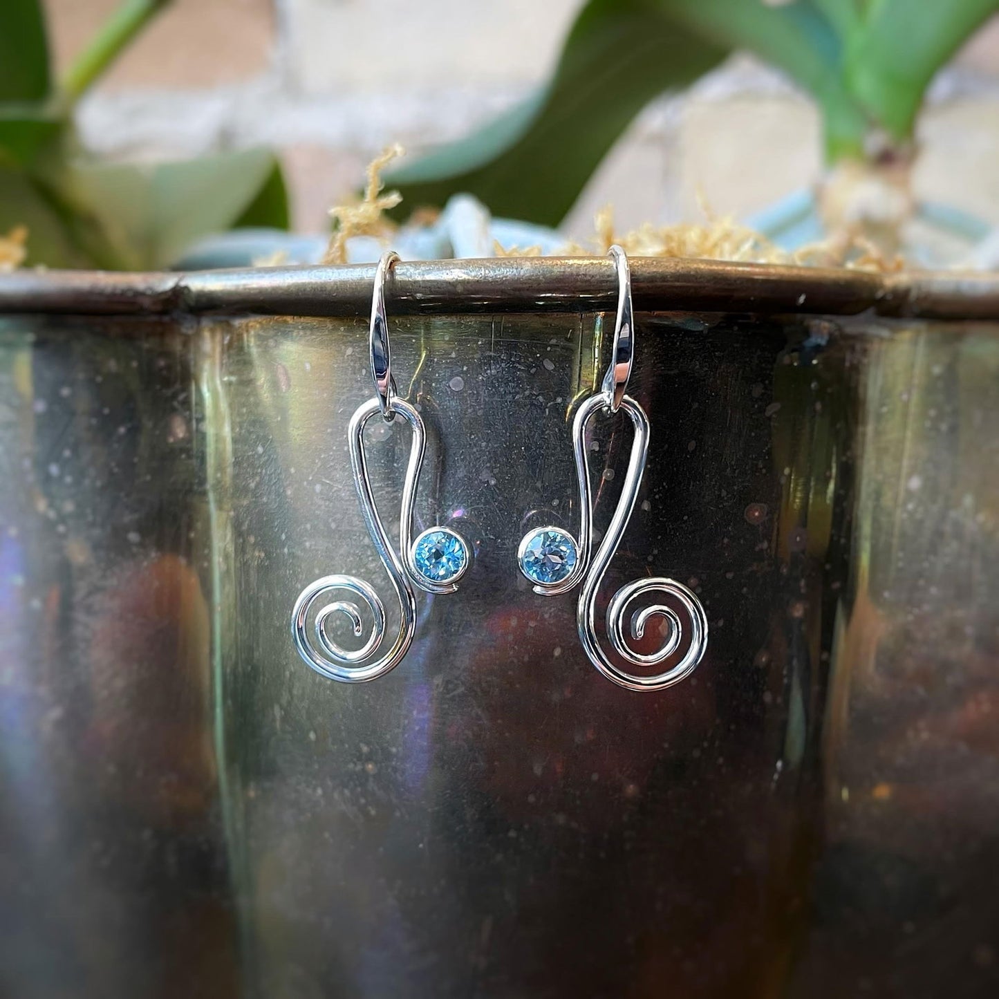 Photo of "Script" Blue Topaz Earrings in a decorative scene, designed by , available at Plumb Gold & Plumb Silver