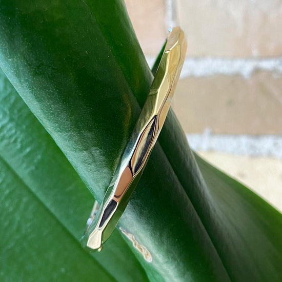 Photo of Shell Bangle Bracelet in a decorative scene, designed by , available at Plumb Gold & Plumb Silver