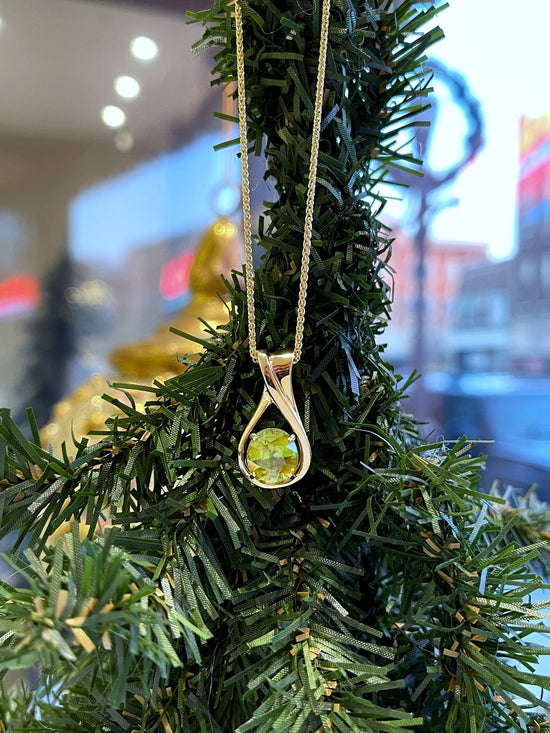 Photo of Sphene Pendant in a decorative scene, designed by , available at Plumb Gold & Plumb Silver