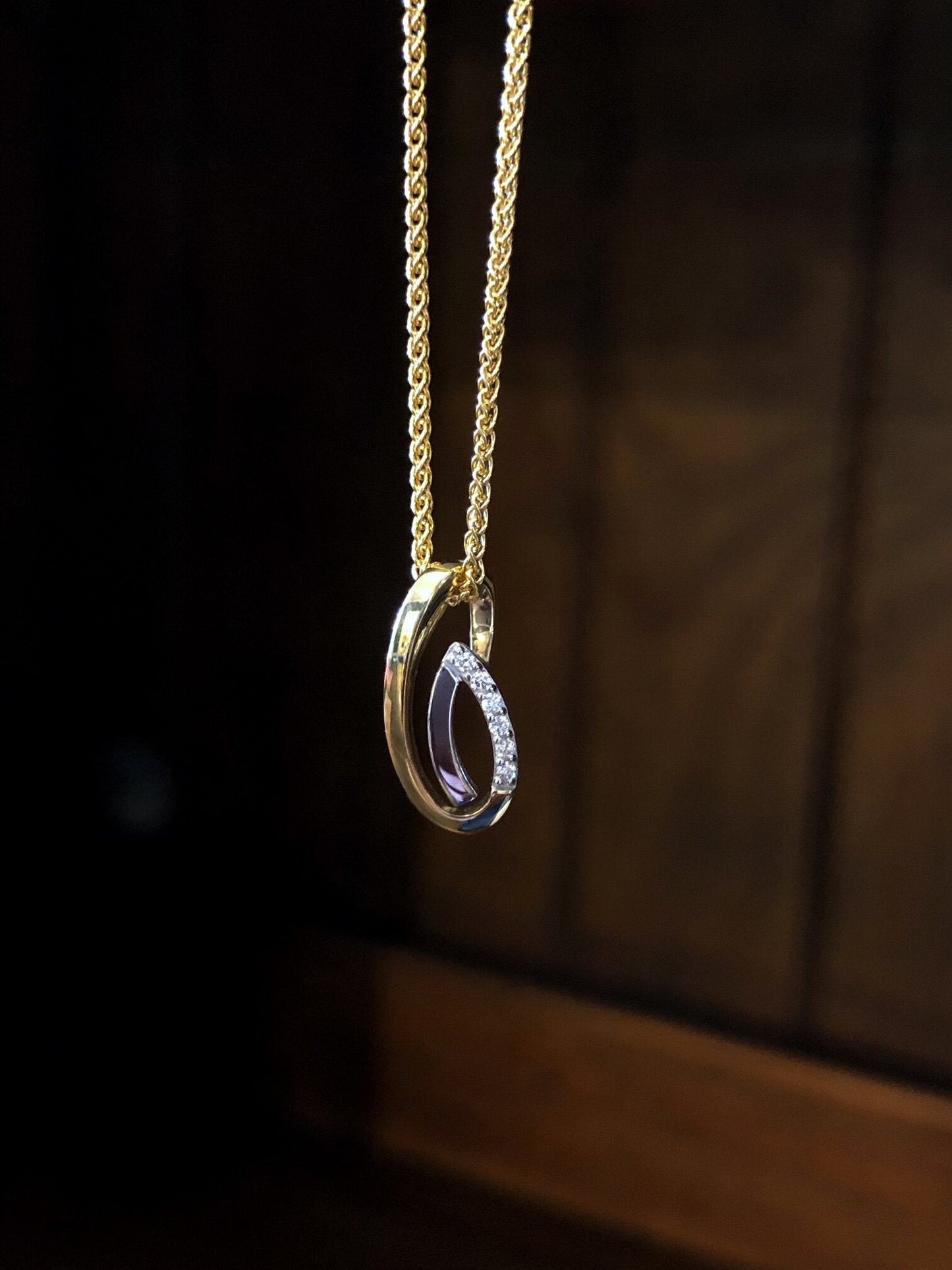 Photo of Spiral Teardrop Pendant in a decorative scene, designed by , available at Plumb Gold & Plumb Silver